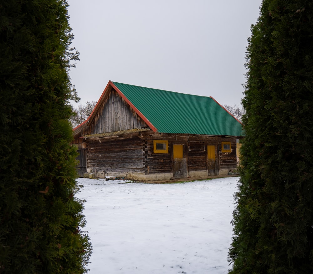 a log cabin with a green roof surrounded by trees