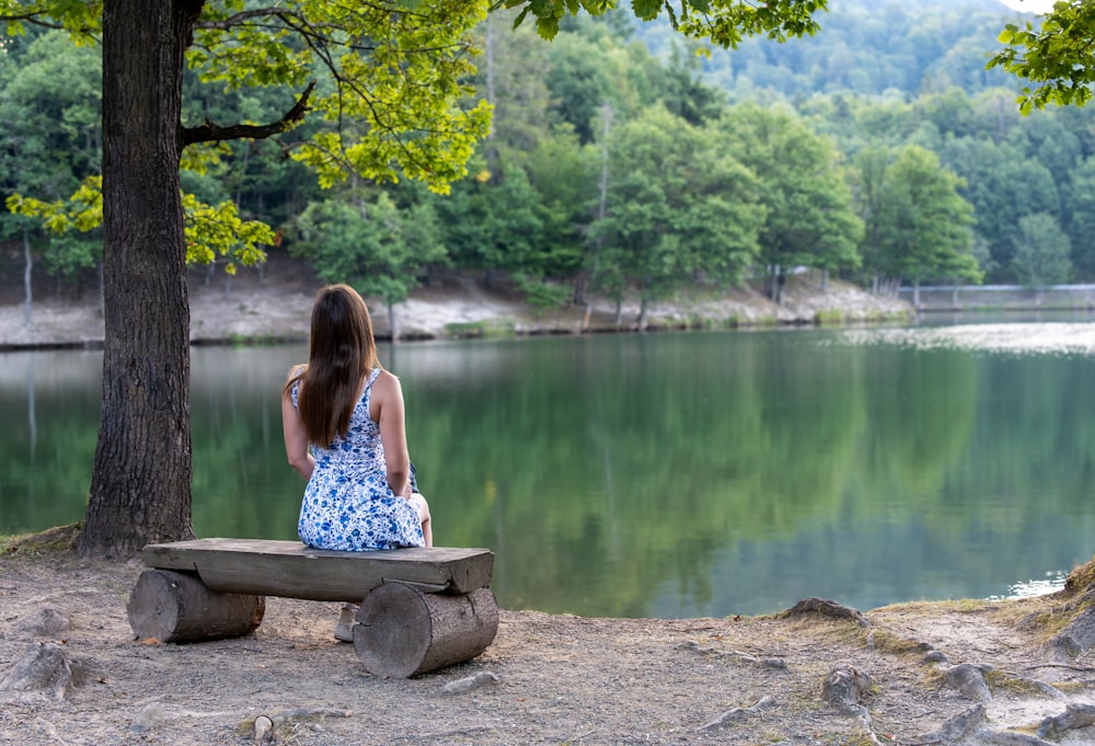 a woman sitting on a bench near a lake