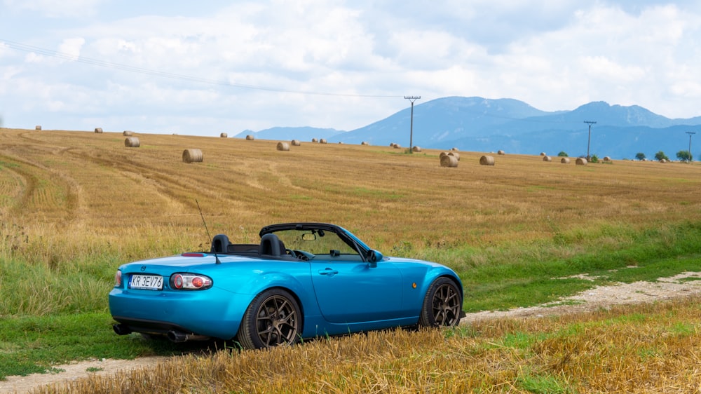 a blue convertible car parked on a dirt road