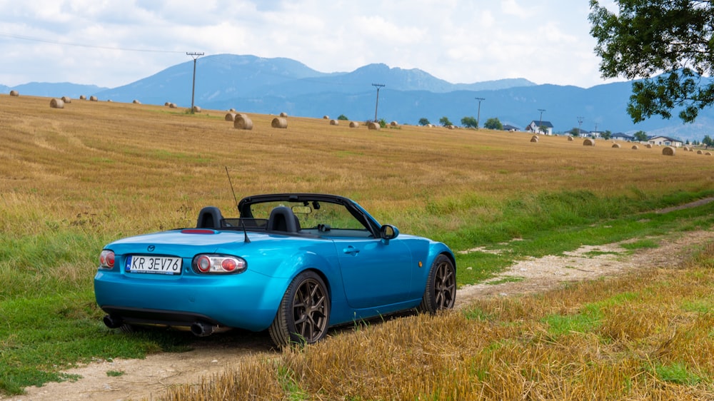 um carro esportivo azul estacionado em uma estrada de terra