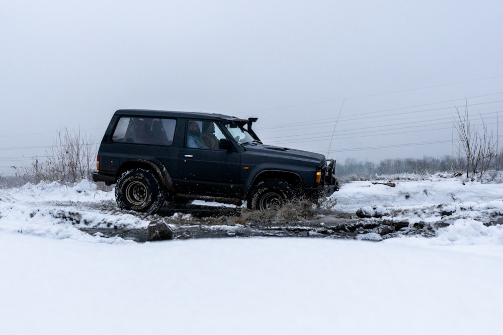 a jeep driving through a puddle in the snow
