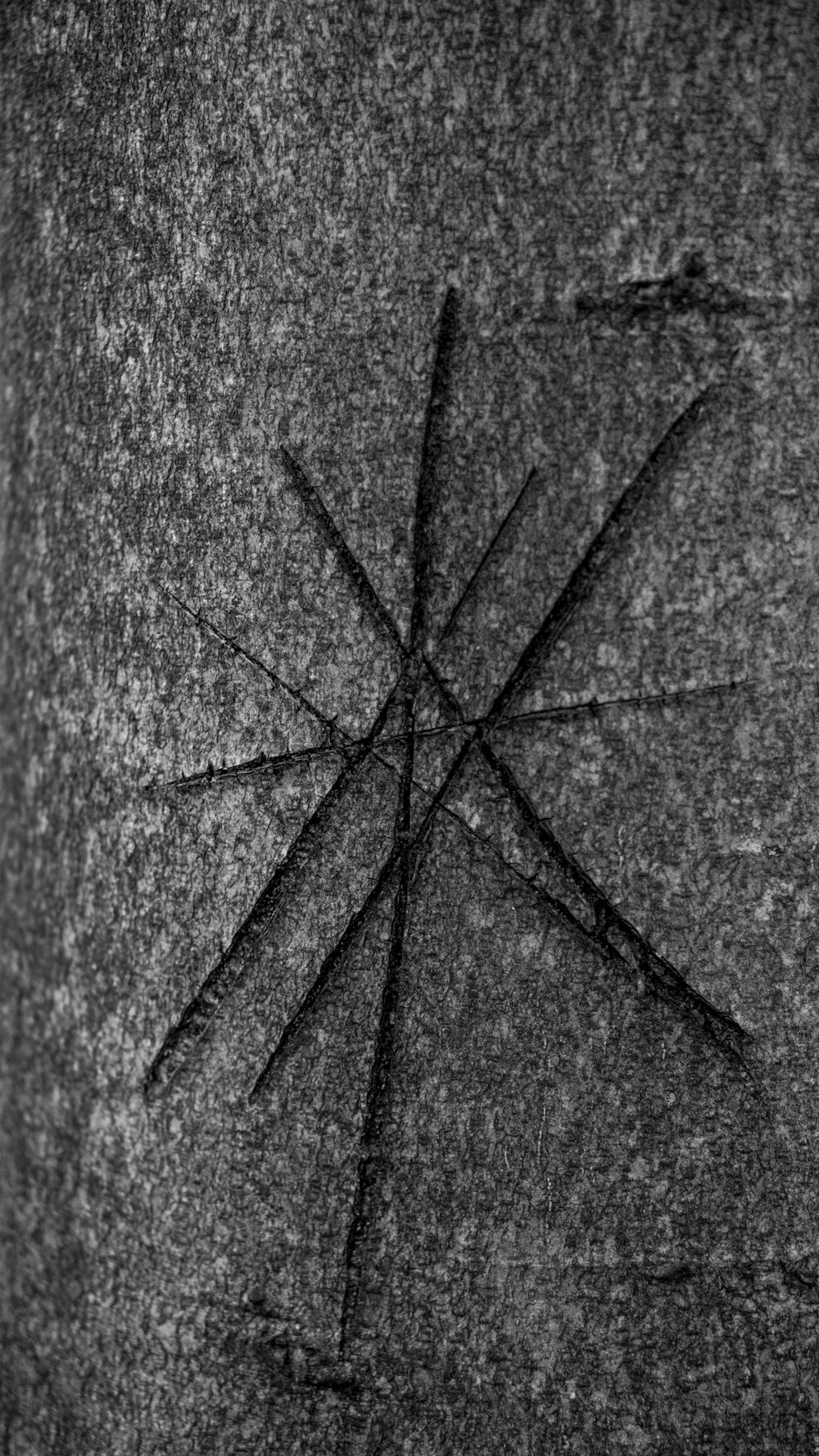 a black and white photo of a cross on a rock
