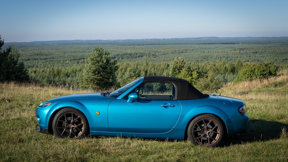 Une voiture de sport bleue garée dans un champ herbeux
