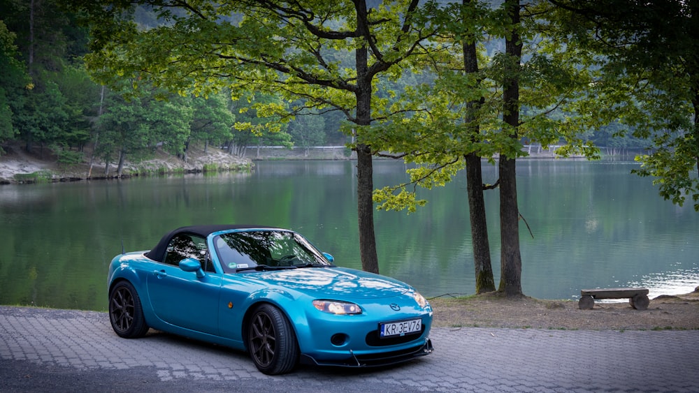 Une voiture de sport bleue garée au bord d’un lac