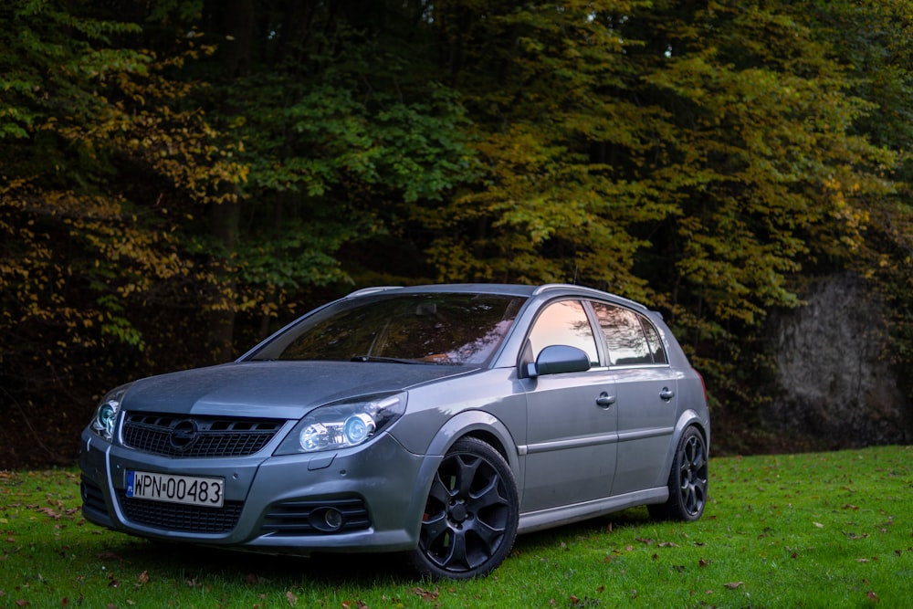 a silver car parked in front of some trees