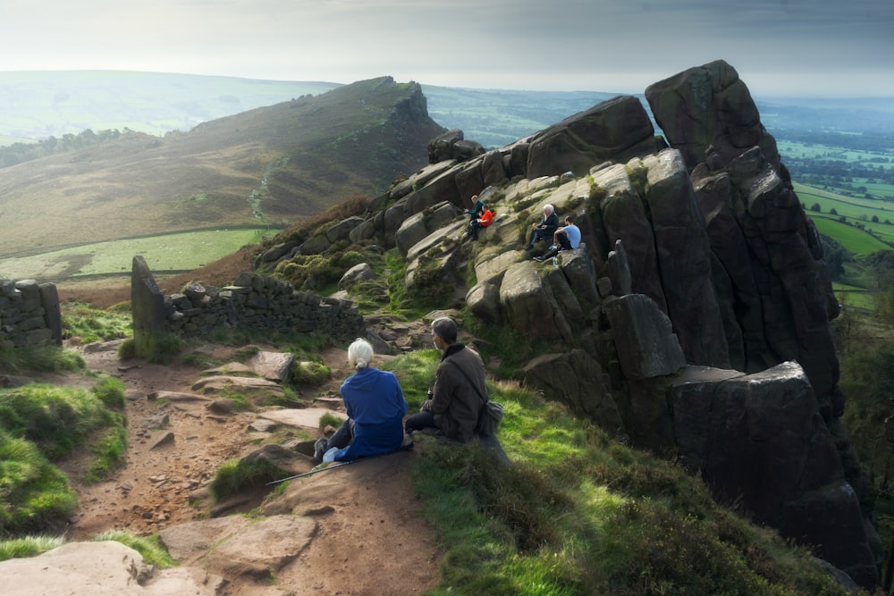 Un par de personas sentadas en la cima de una montaña