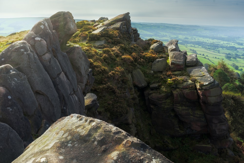 a rocky outcropping with a grassy valley in the background