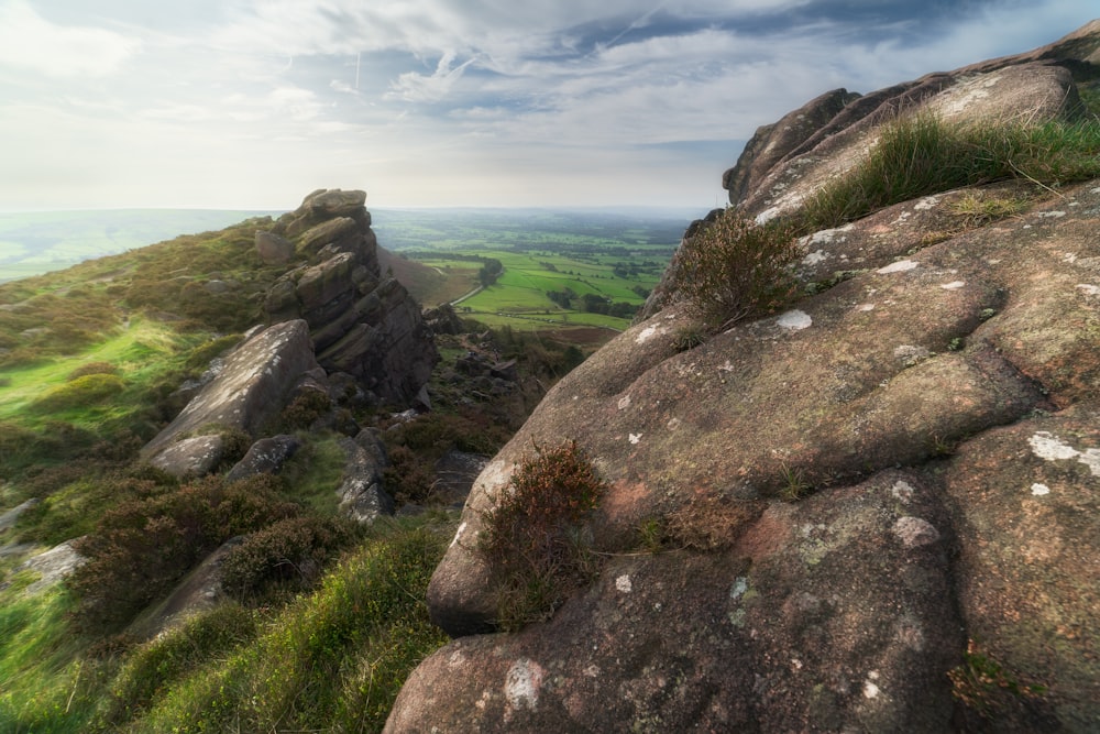 a view of a rocky outcropping with green fields in the distance