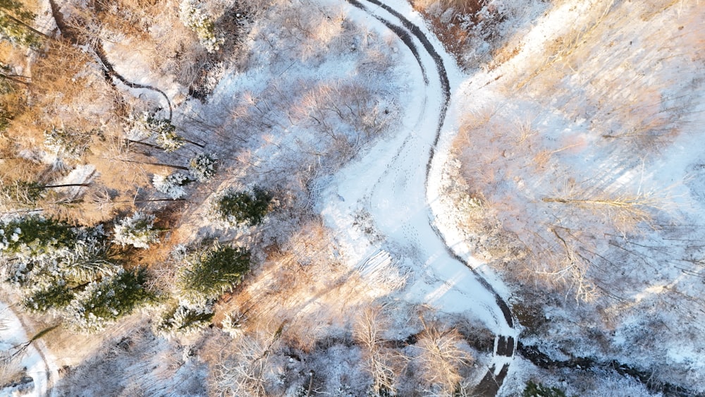 an aerial view of a snowy road in the woods