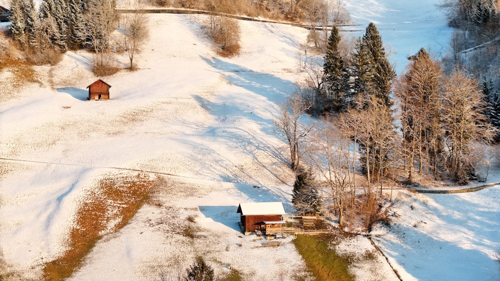 an aerial view of a small cabin in the middle of a snowy field