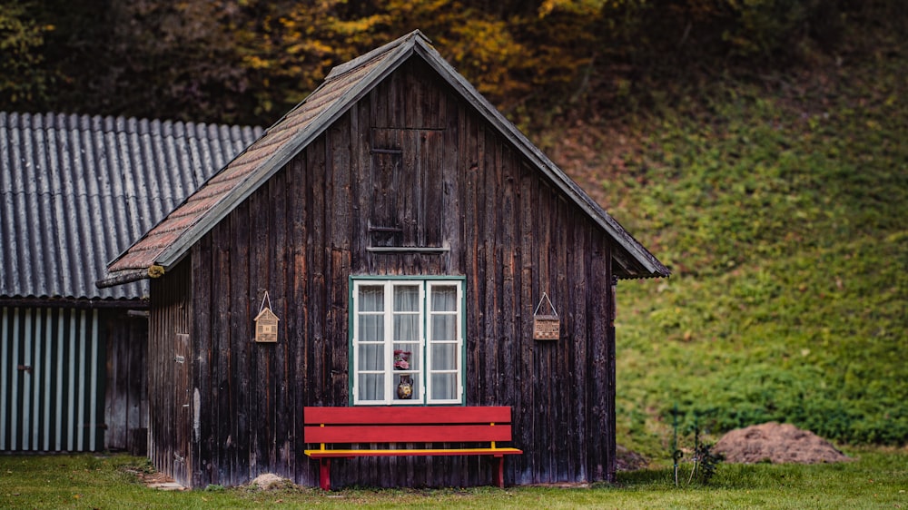 a red bench sitting in front of a wooden building