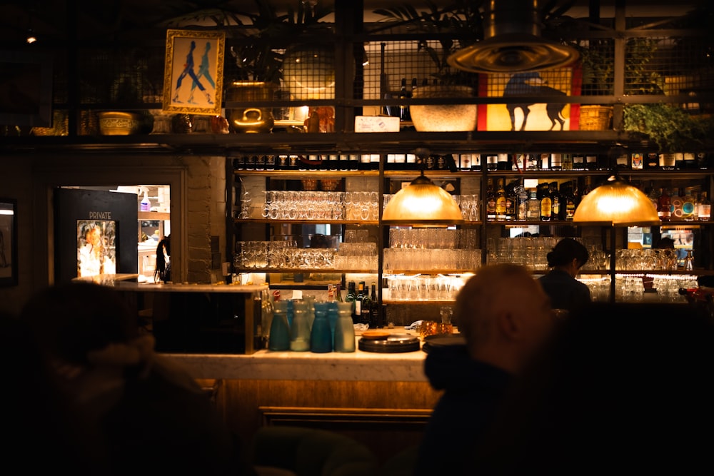 a dimly lit bar with people sitting at the bar