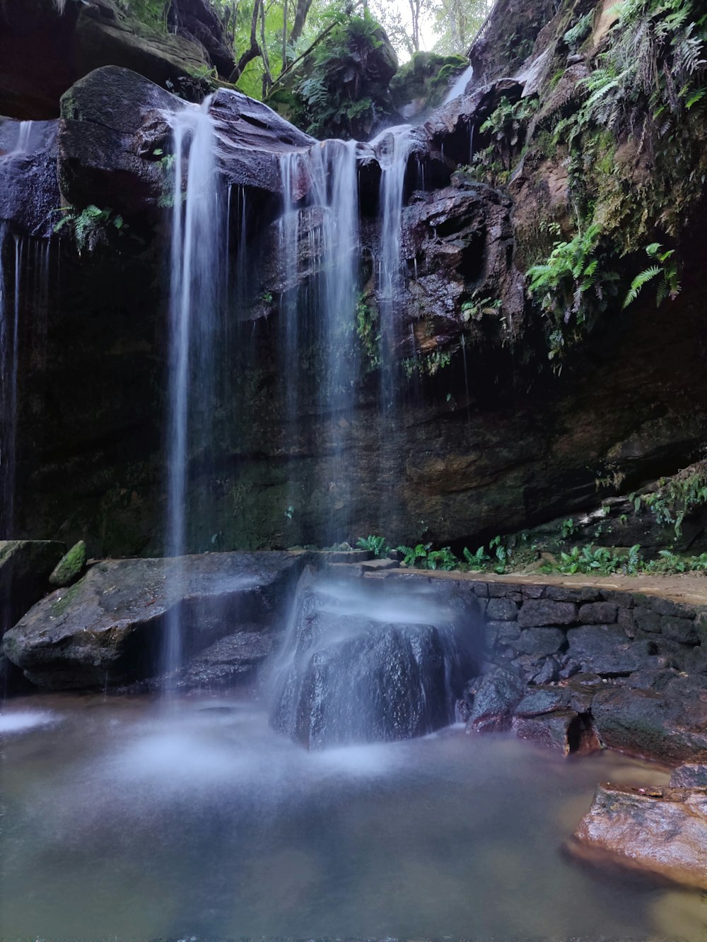 a small waterfall in the middle of a forest