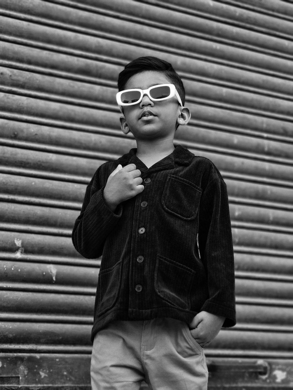 a young boy wearing sunglasses standing in front of a building