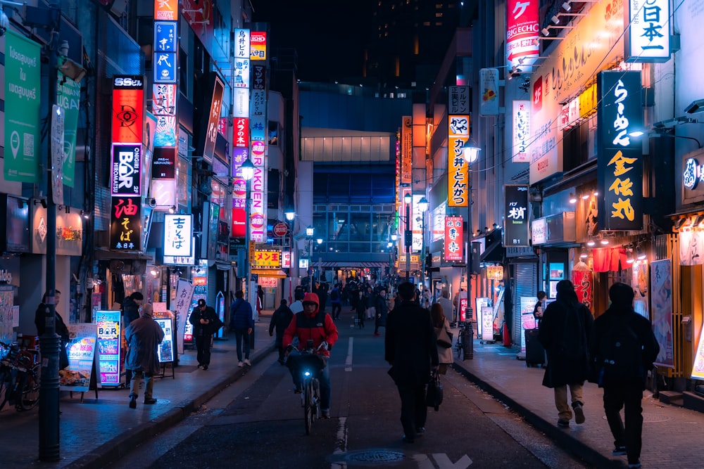 a group of people walking down a street at night