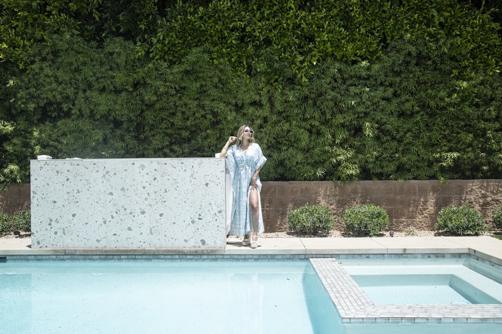 a woman standing next to a swimming pool