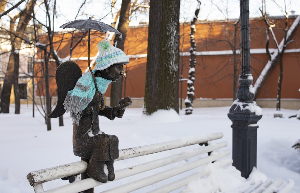 a statue of an angel sitting on a bench in the snow