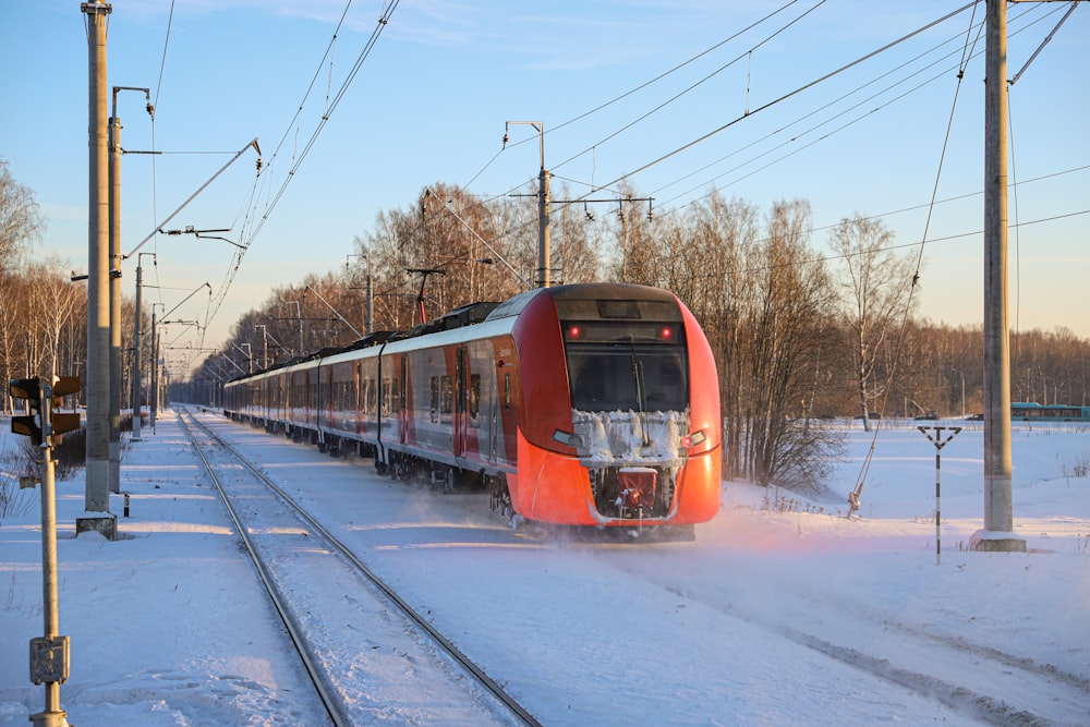 a red train traveling down train tracks next to a forest