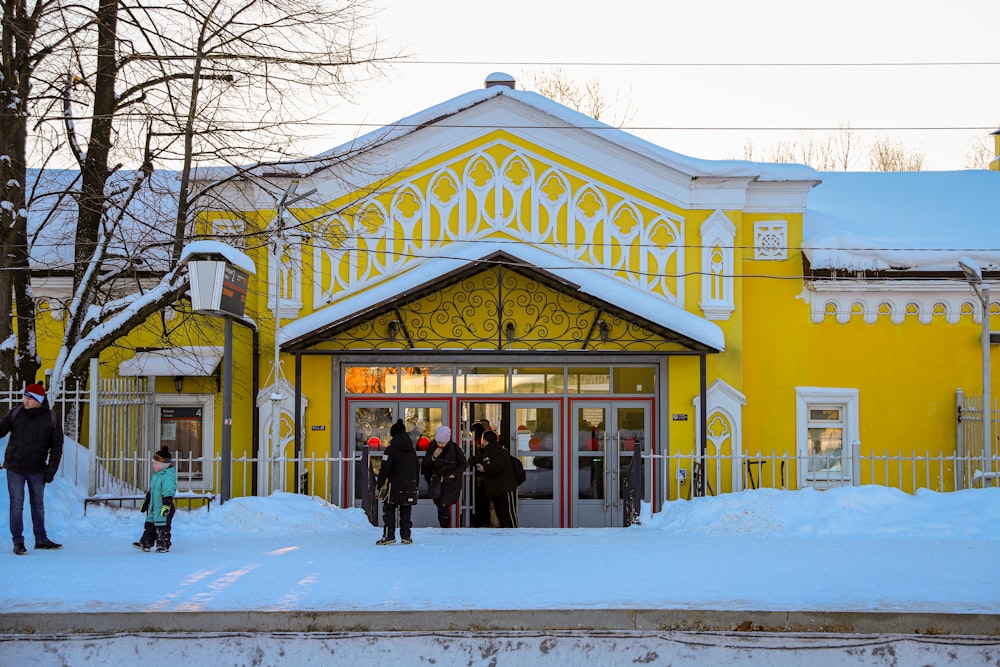 a group of people standing outside of a yellow building