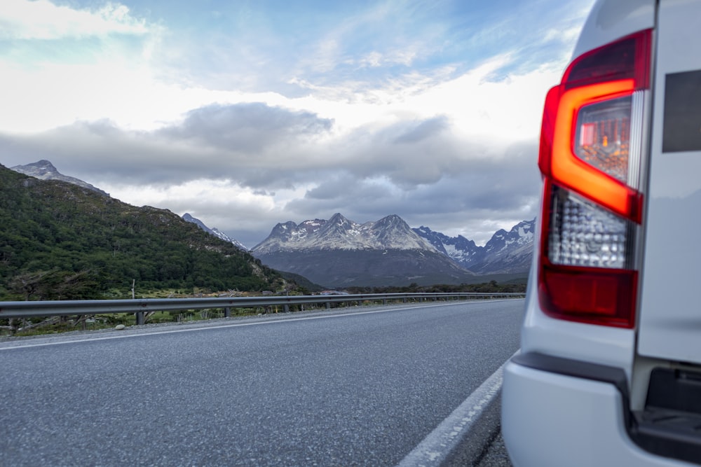 Un coche conduciendo por una carretera con montañas de fondo