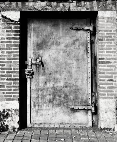 Black and white photograph of a secured door, evoking the layers of security required to protect precious metals