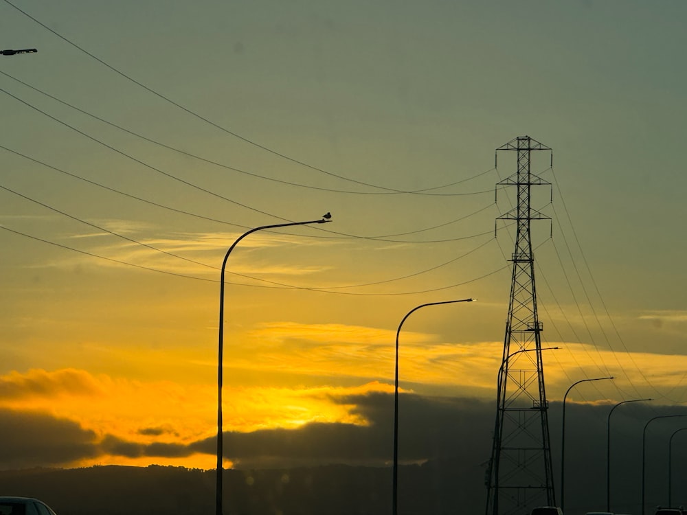 the sun is setting behind power lines and cars