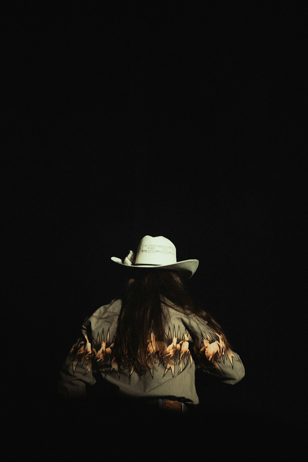 a woman wearing a cowboy hat in the dark