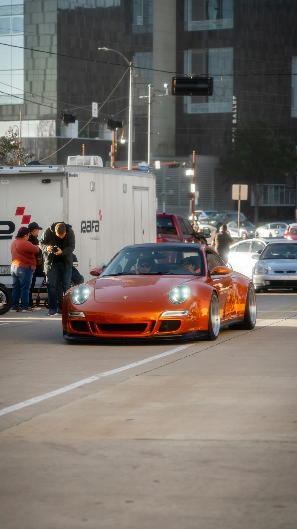 an orange sports car driving down a city street