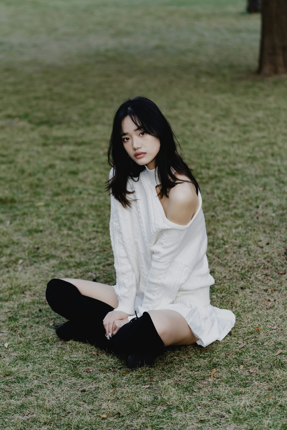 a woman sitting on the ground in a field