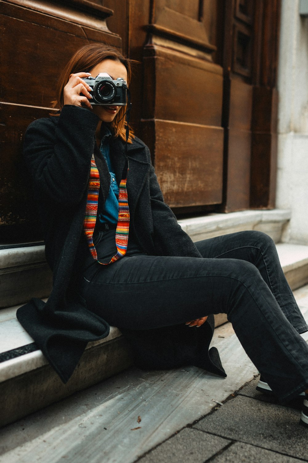 a woman sitting on a step taking a picture with a camera