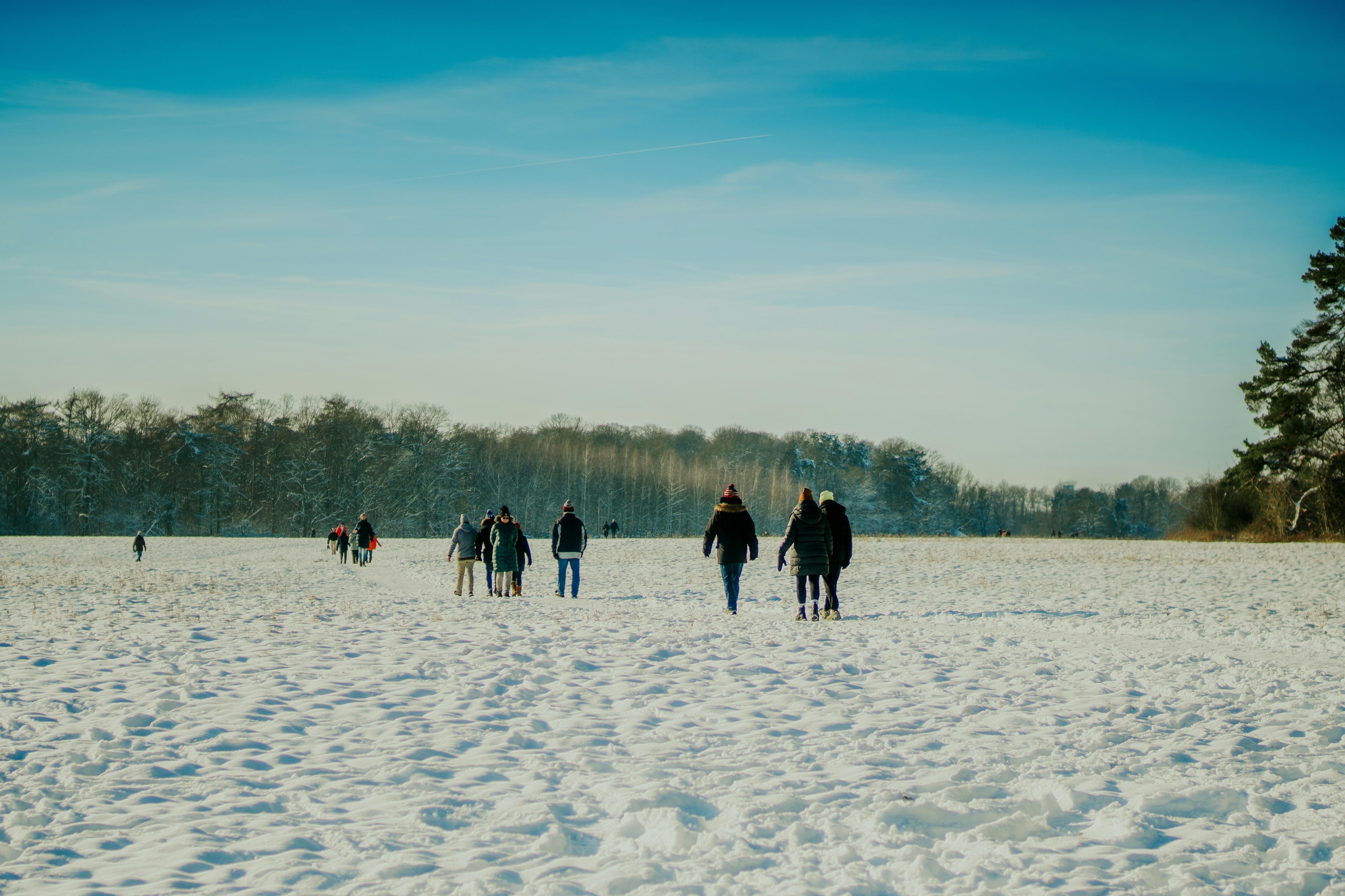 a group of people walking across a snow covered field
