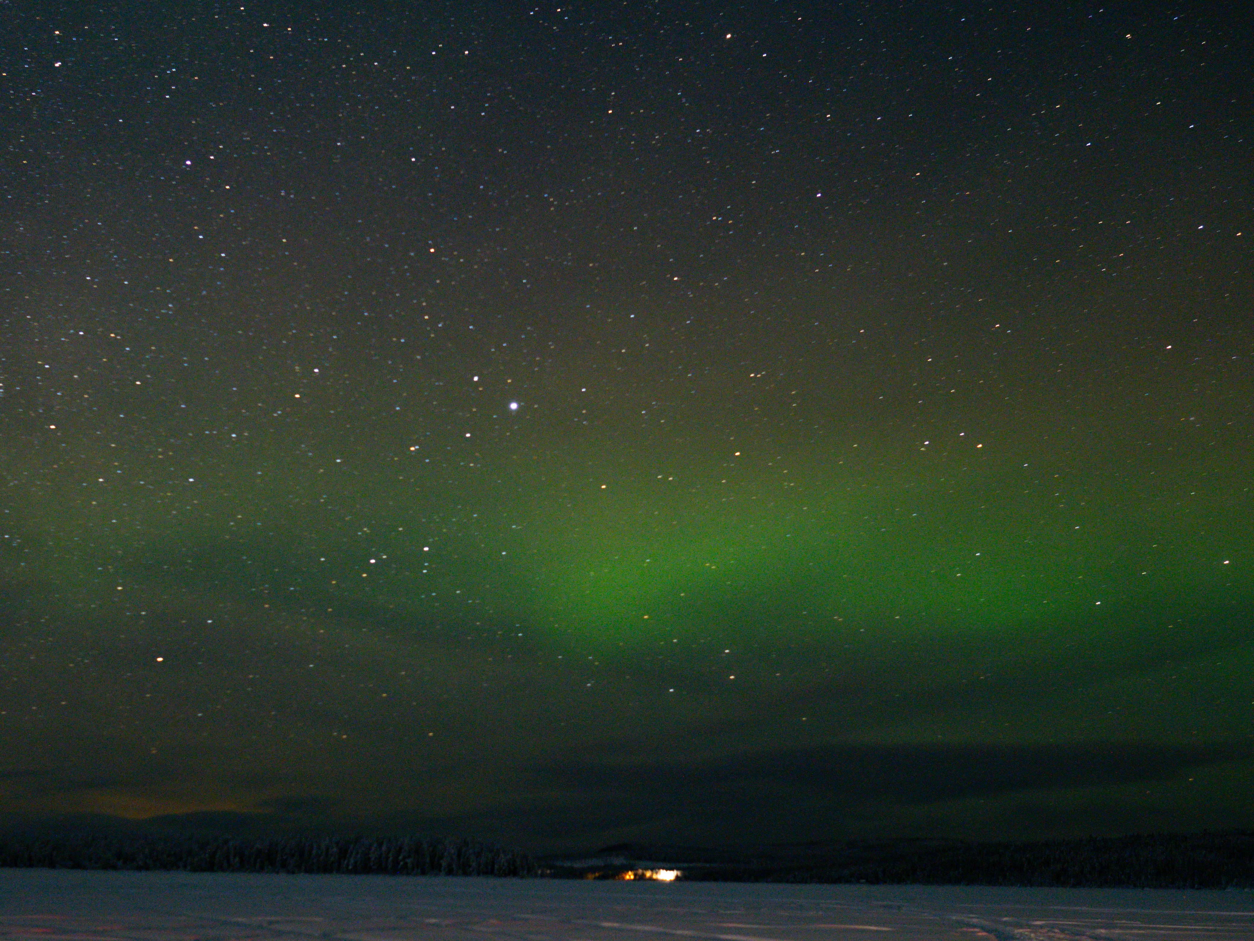 uma aurora verde e branca sobre um campo coberto de neve