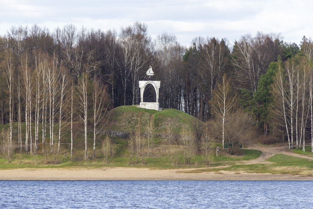 a small white tower sitting on top of a lush green hillside