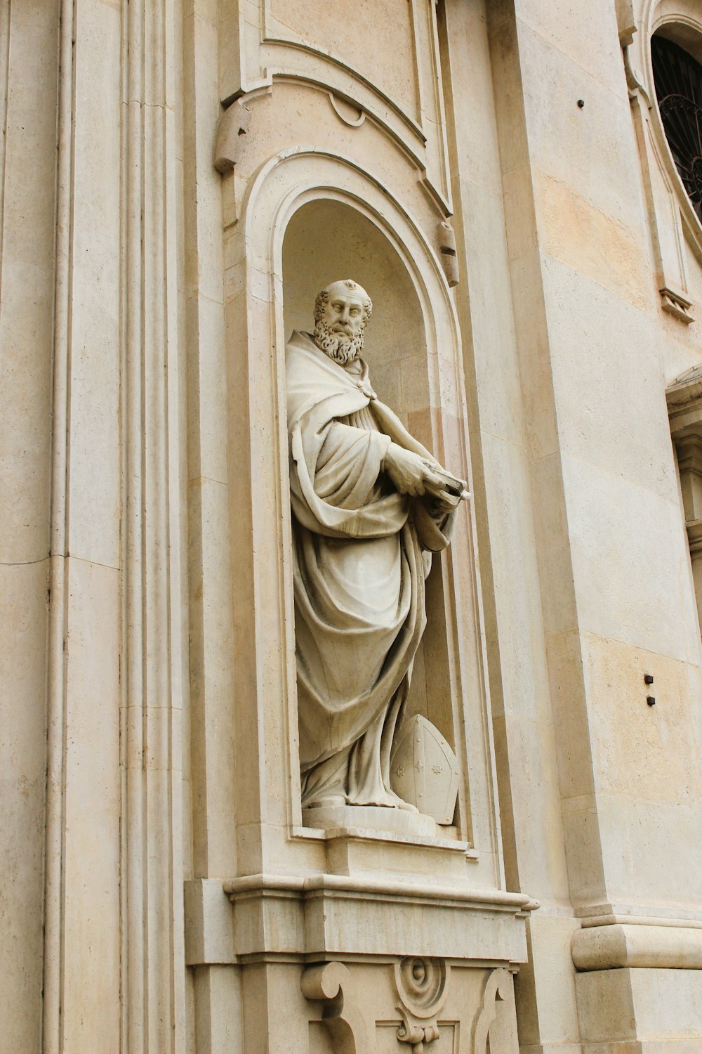 uma estátua de um homem segurando um livro em frente a um edifício