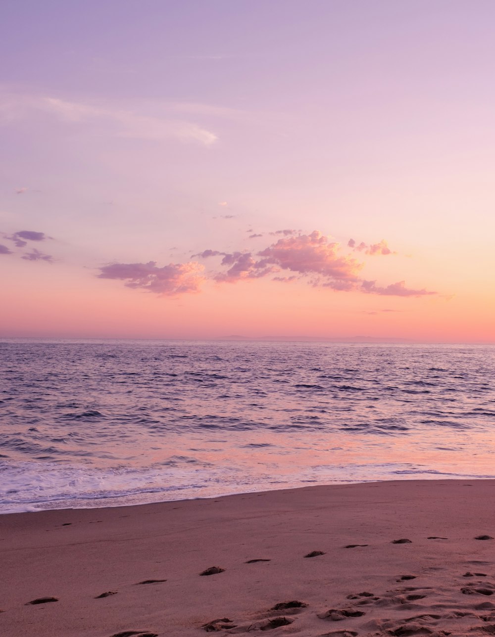 a person walking on a beach with a surfboard