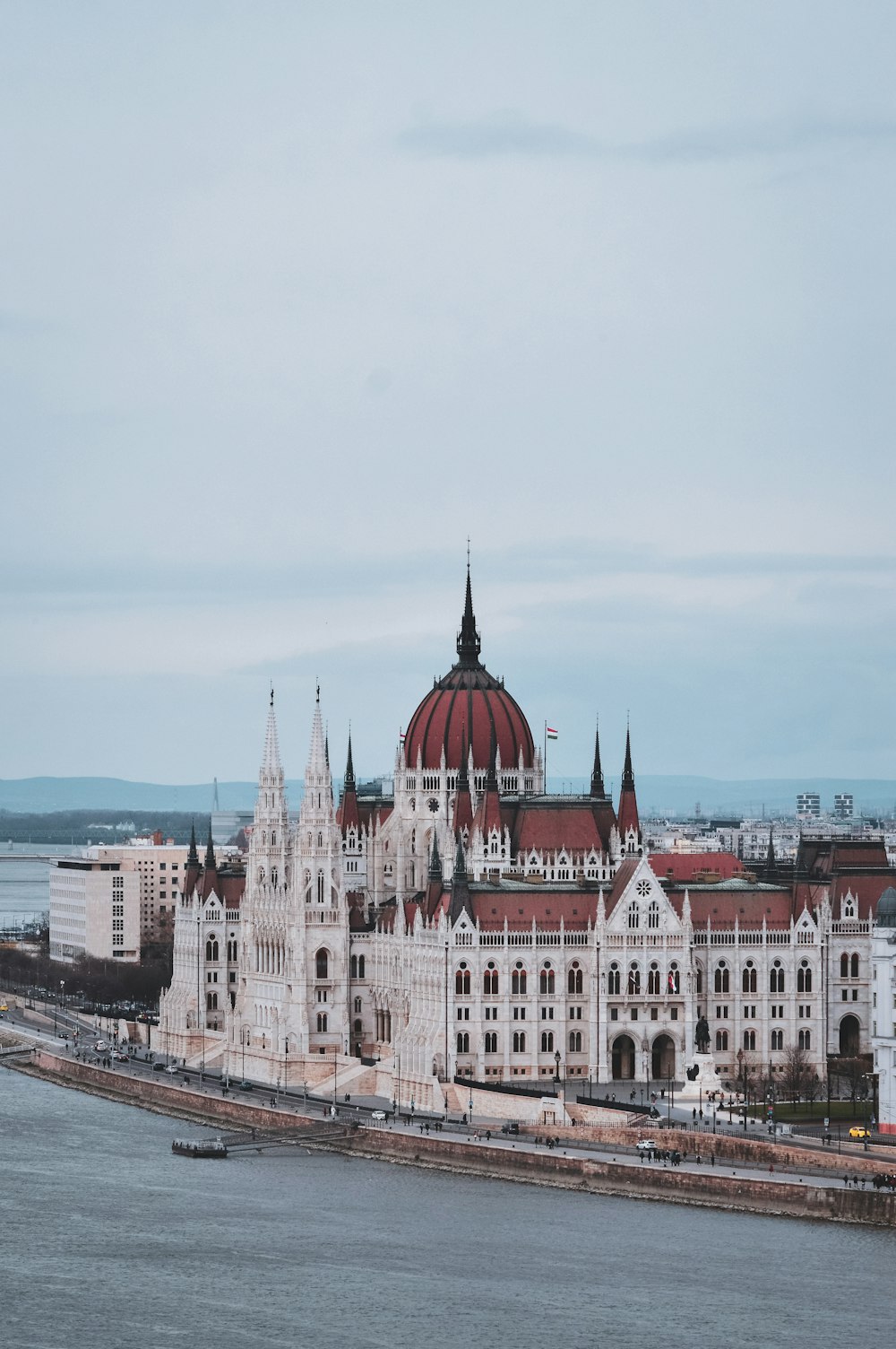 a large white building with a red roof next to a body of water