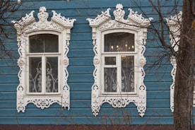 a blue building with two windows and a clock