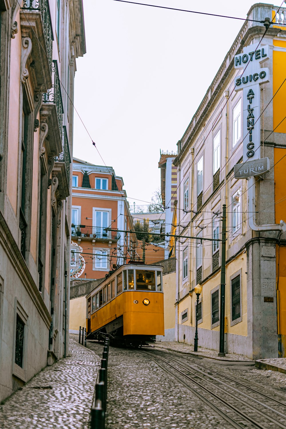a yellow trolley is going down a cobblestone street