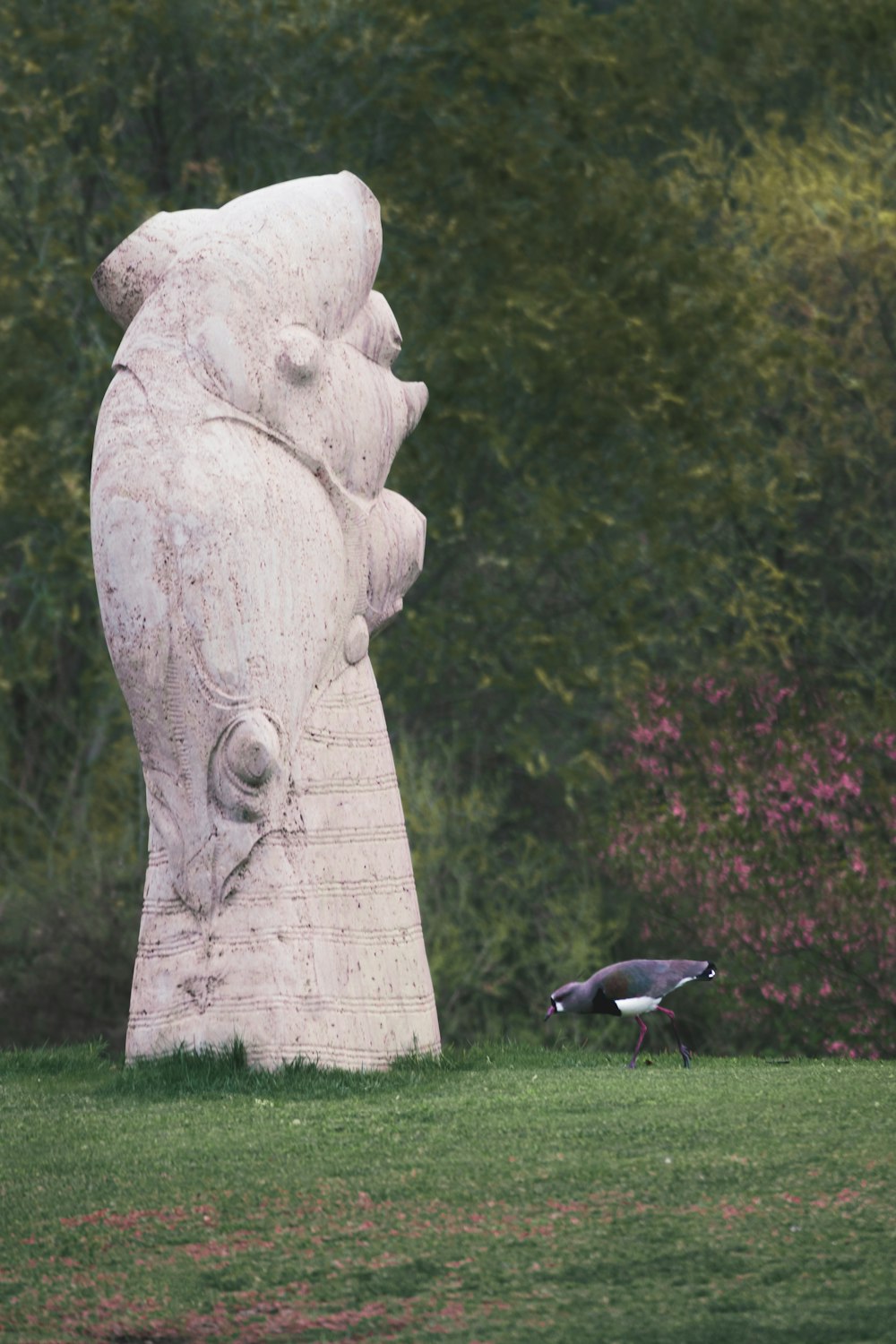 a bird standing next to a statue of a bear