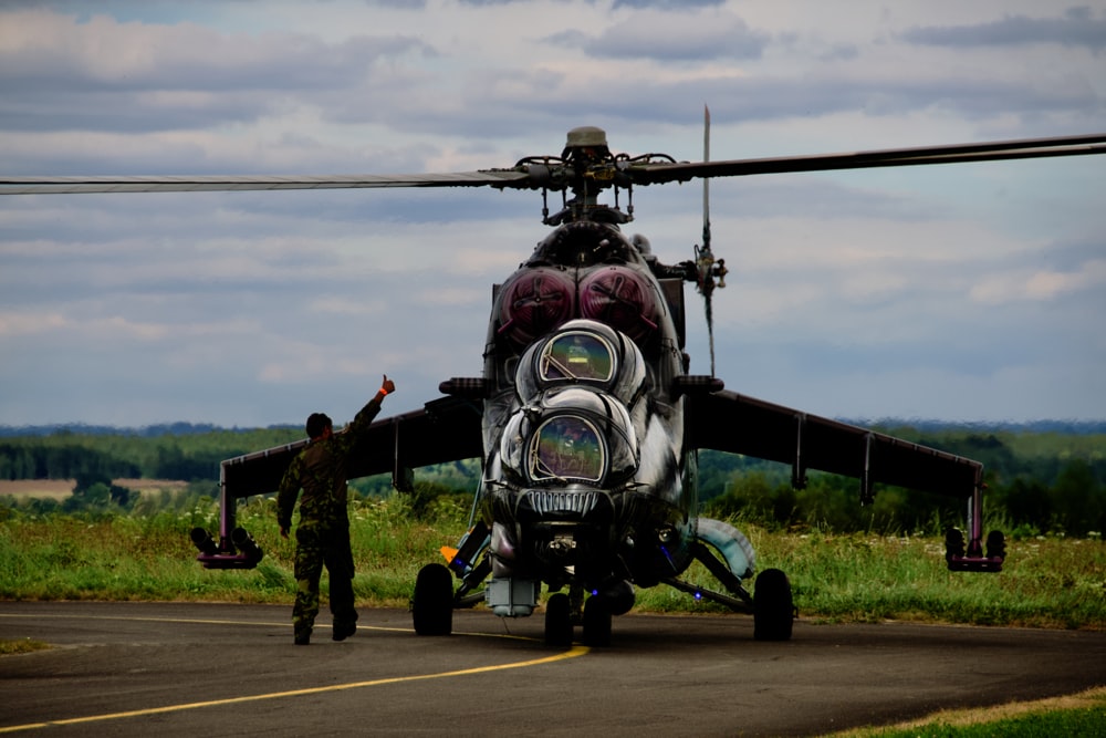 Un hombre de pie junto a un helicóptero en una pista