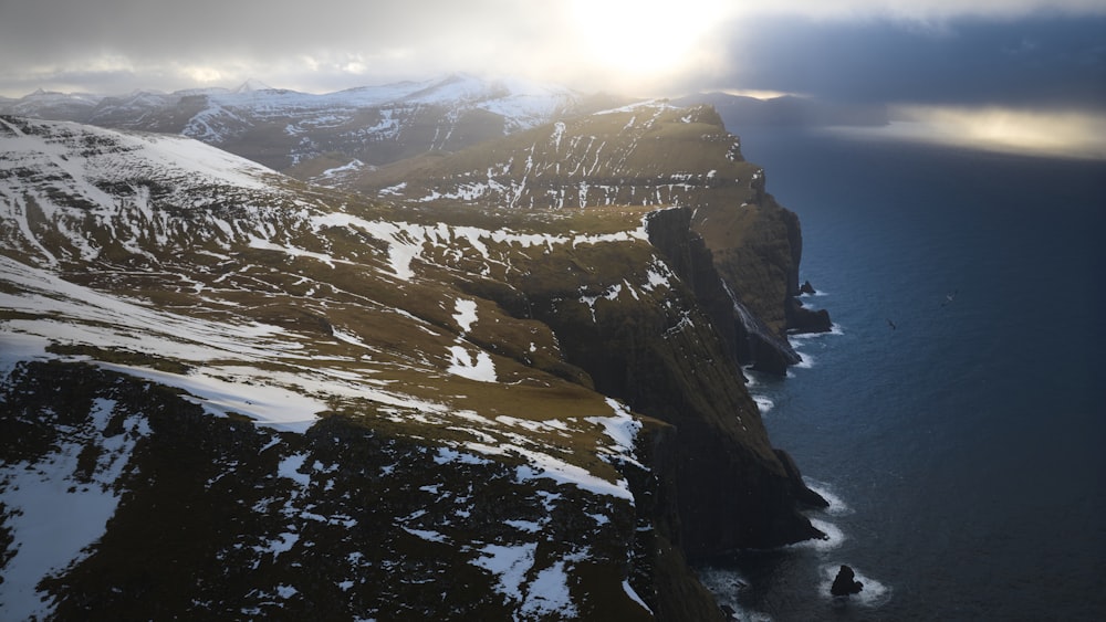 an aerial view of snow covered mountains and a body of water