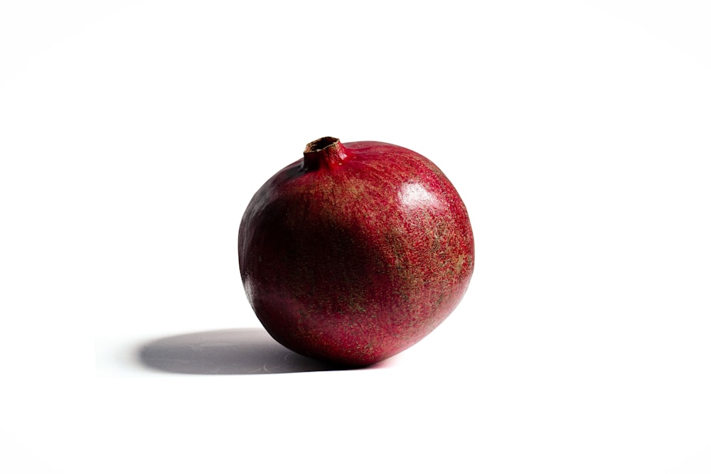 a red apple sitting on top of a white table