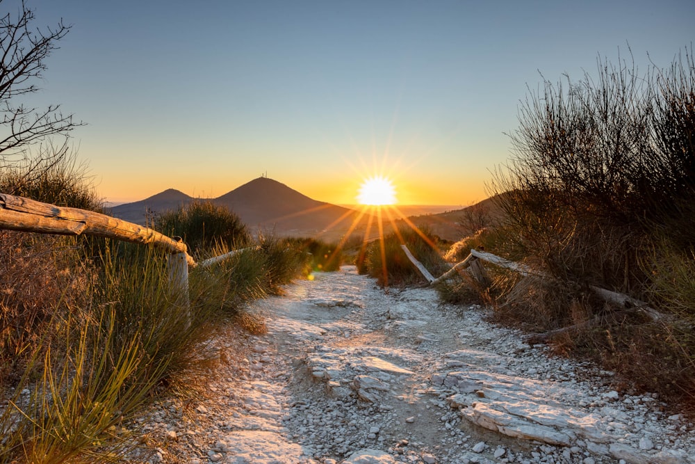 the sun is setting over a rocky trail