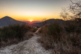 the sun is setting on a mountain trail