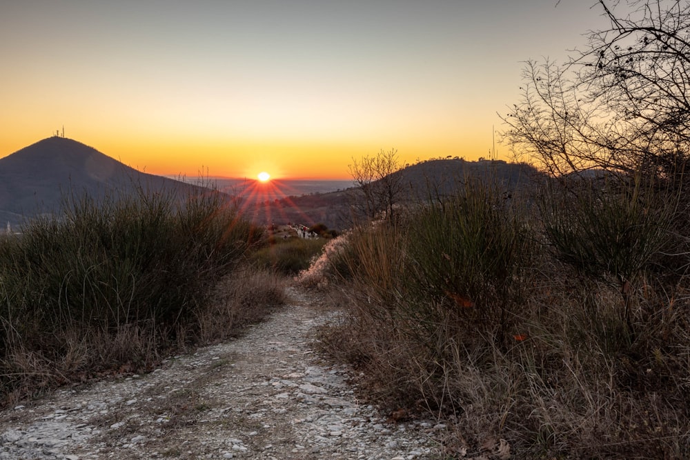 the sun is setting on a mountain trail