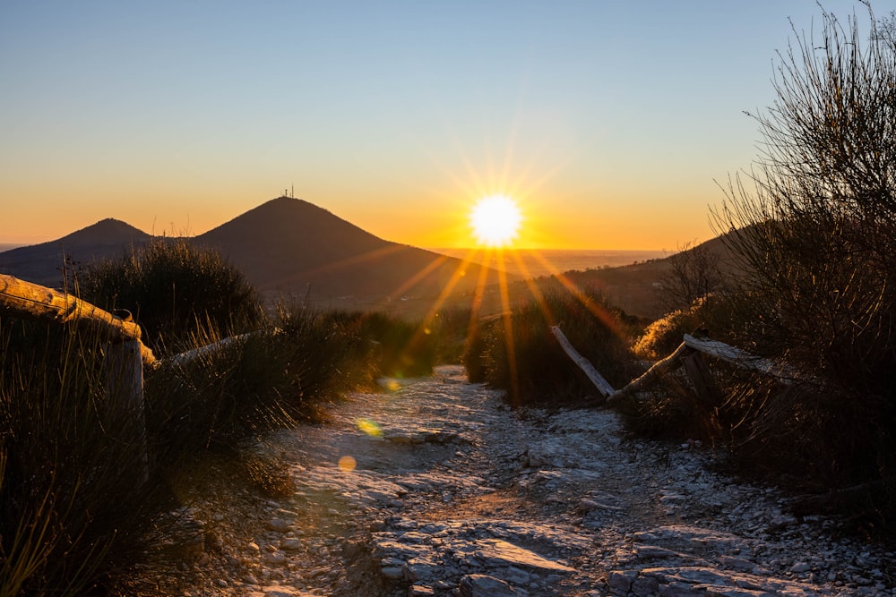 the sun is setting over the mountains in the distance