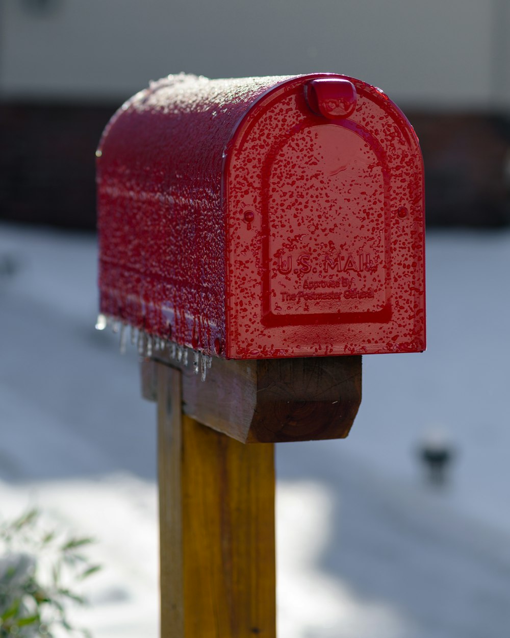 un buzón rojo sentado encima de un poste de madera