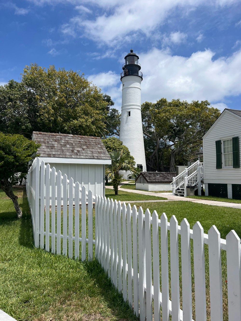 a white picket fence with a lighthouse in the background
