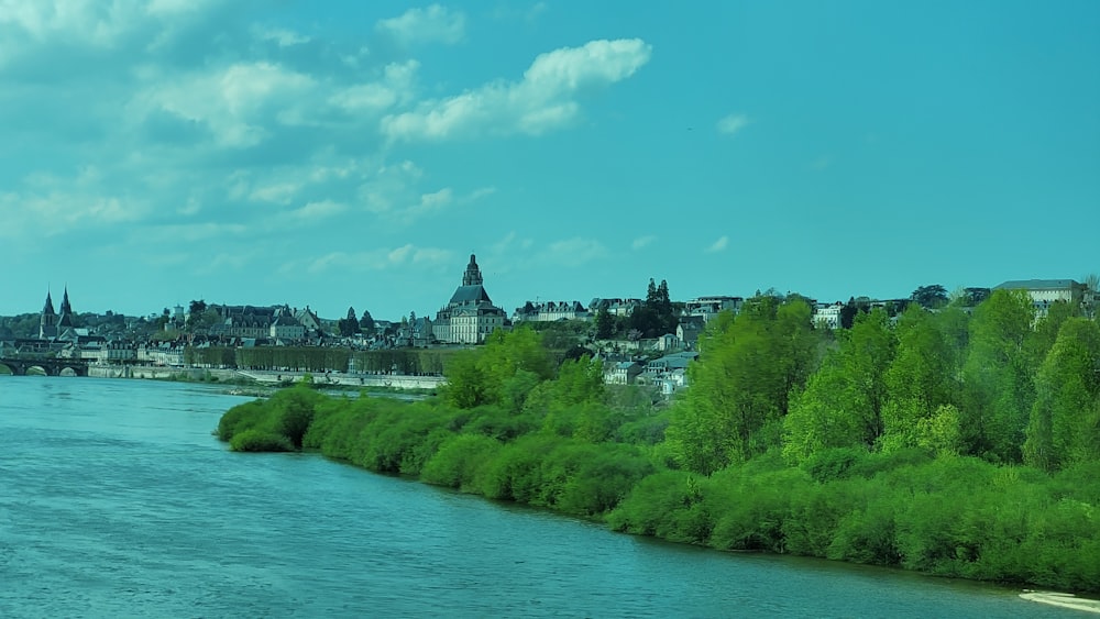 a river running through a city next to a lush green forest