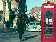 a woman walking down a street next to a police car